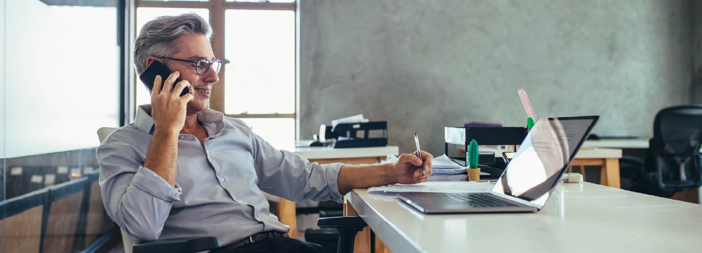 A businessman reclining in an office chair while on the phone.
