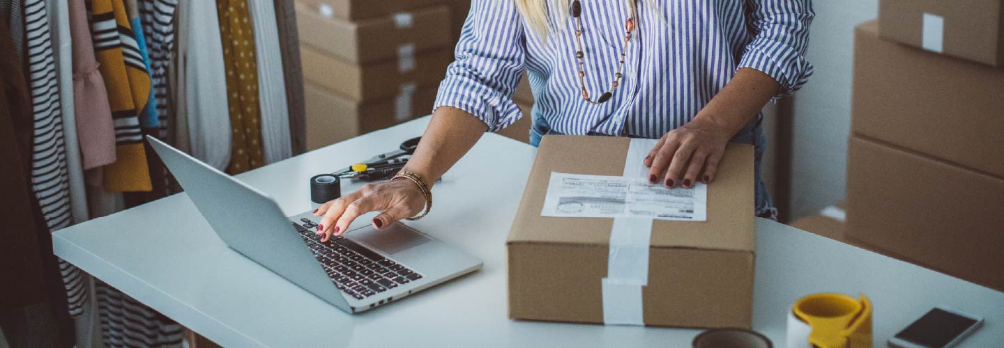 A person's hands over a cardboard box and a laptop.