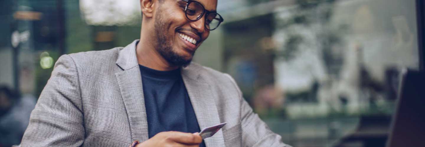 Man in suit jacket an wearing glasses holds a credit card