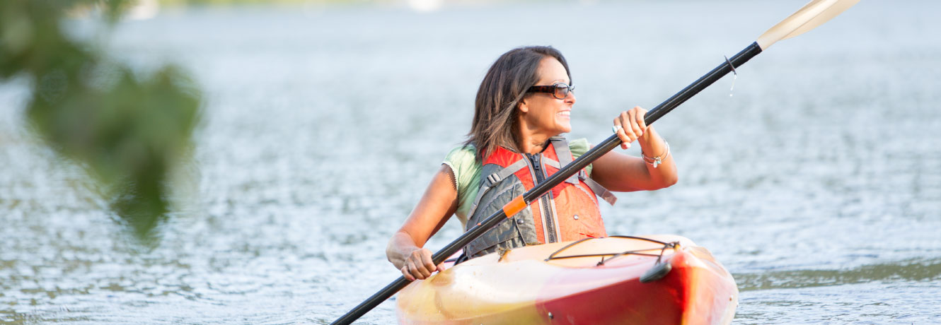 Smiling middle aged woman in kayak on a calm lake.