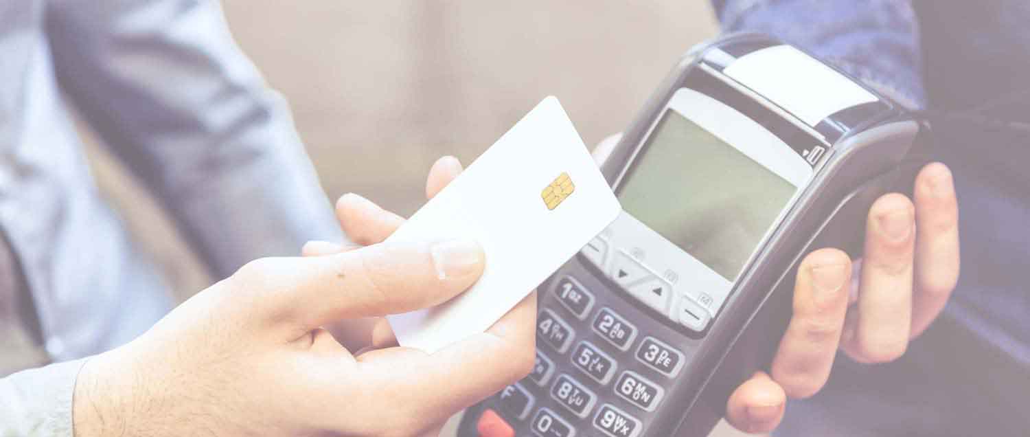 Person holds debit card up to card reader for merchant transaction.