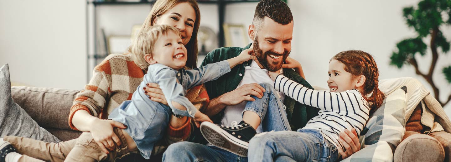 A young family playing together on a couch.