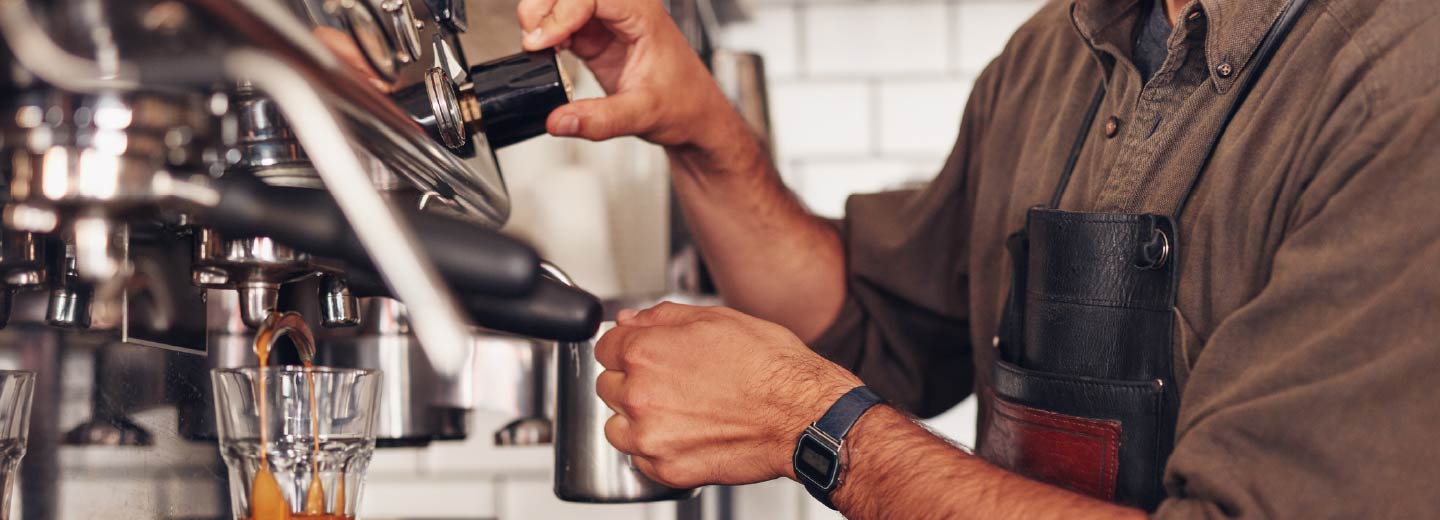 Close up of someone's hands using an industrial coffee machine.