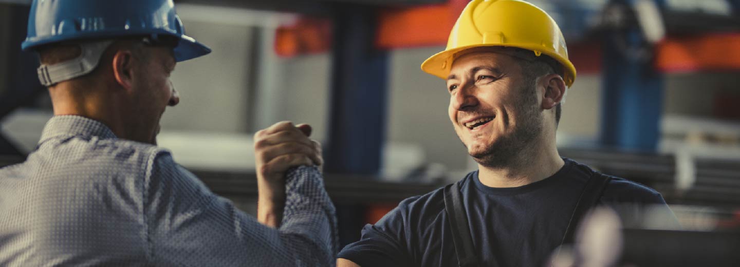 Two men in hard hats shaking hands.