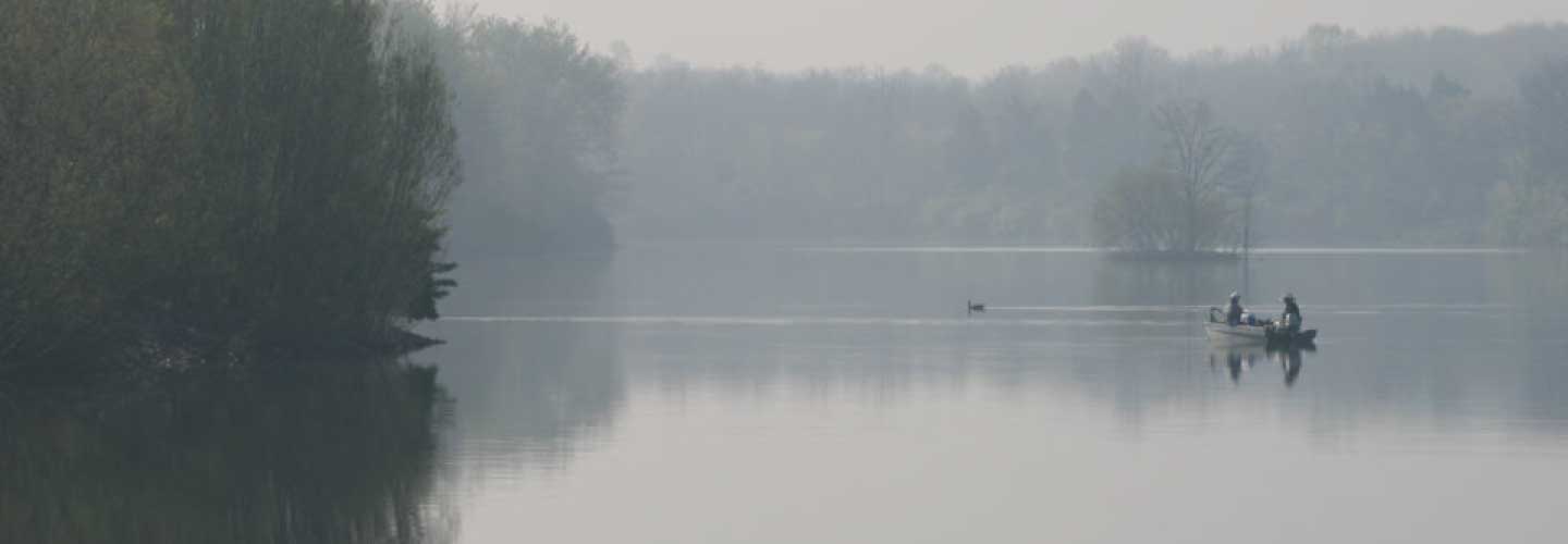 Two people in a boat, fishing in the early morning fog on Lake Reba in Richmond, KY.