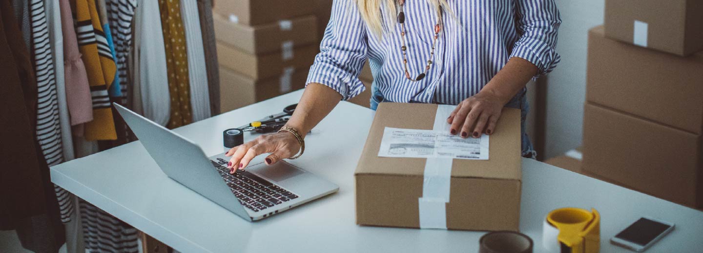 A person's hands over a cardboard box and laptop.
