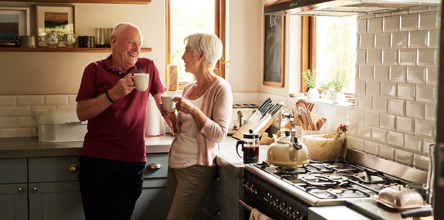 An older couple standing together in a kitchen.