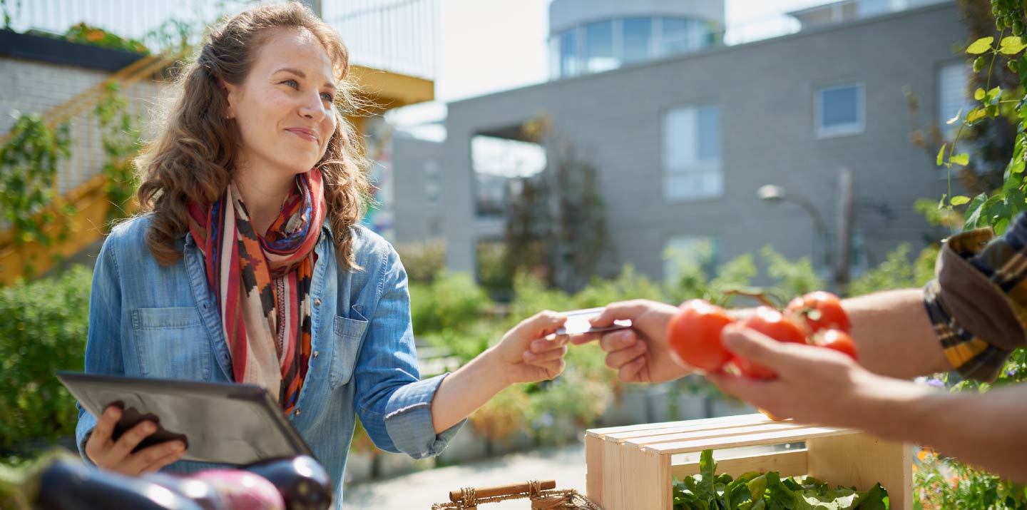 A woman exchanging payment for tomatoes.