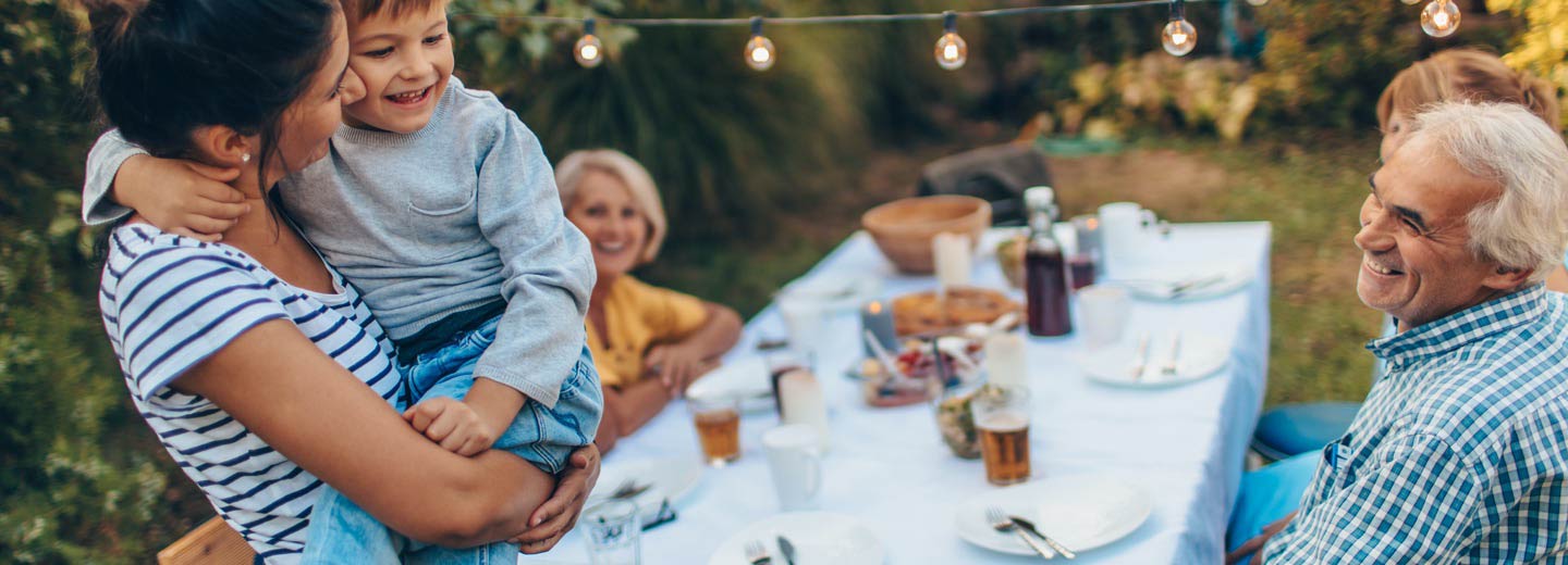 A large family at a dining table outside.