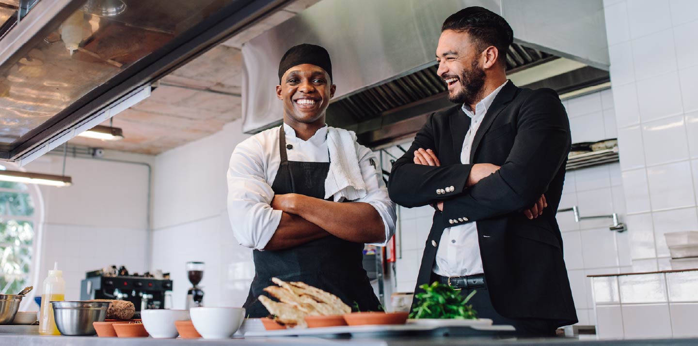 Two businessmen standing in a commercial kitchen.