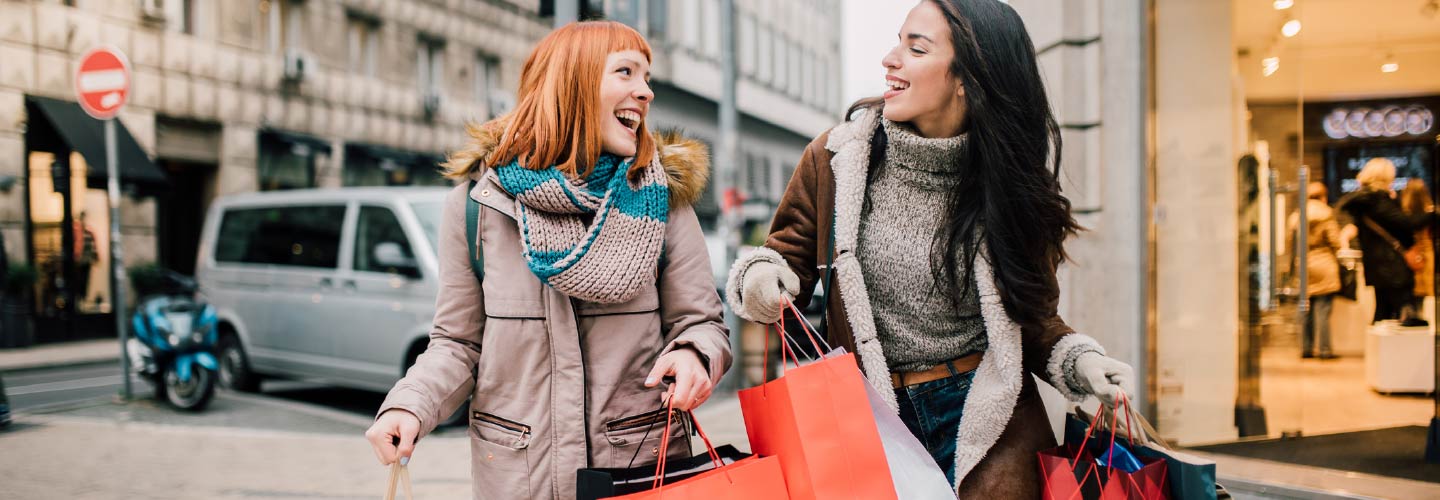 Two friends holding shopping bags.